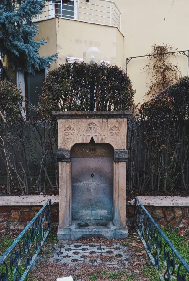 Bahçede taş oymalı bir çeşme.