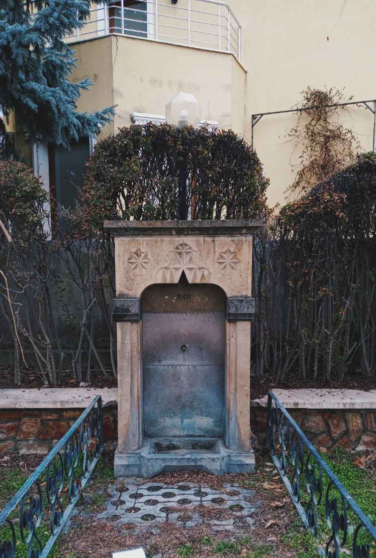 Bahçede taş oymalı bir çeşme.