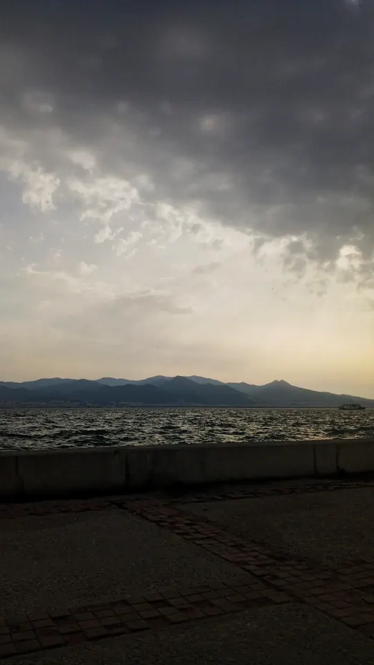 Bulutların arasından sızan ışık, karşıda dağlar. Deniz o gün sakindi.