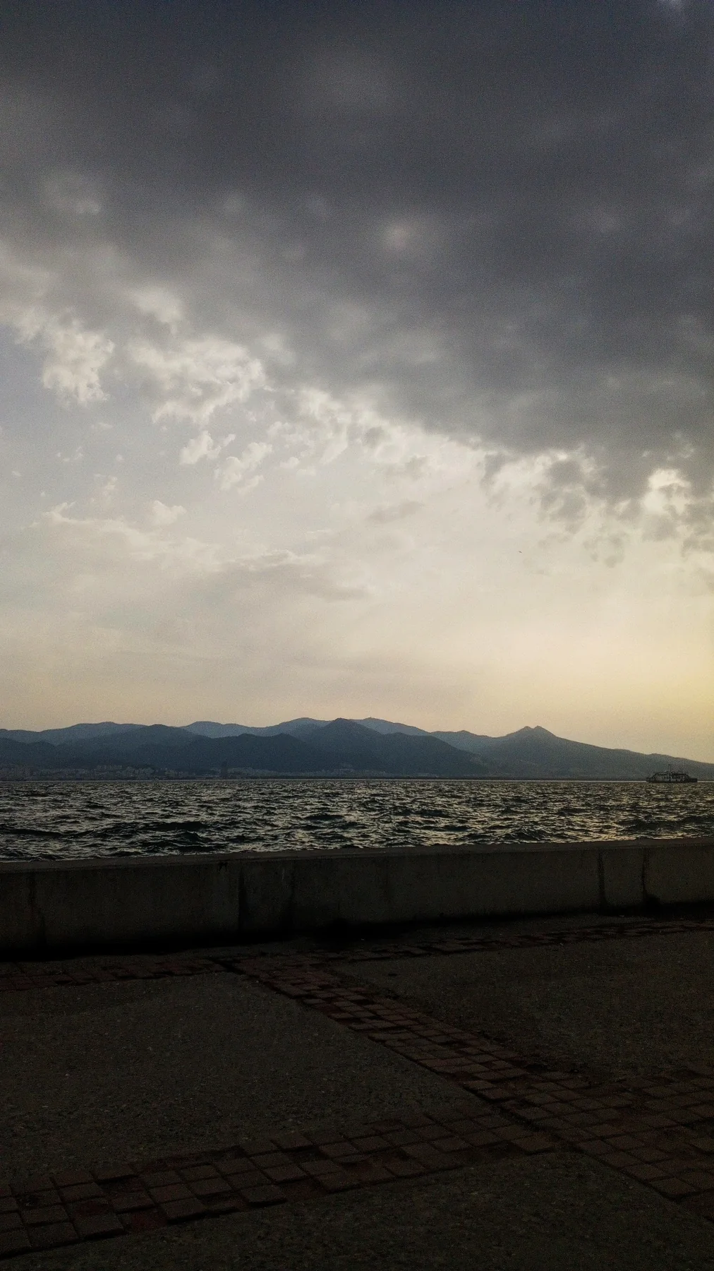Bulutların arasından sızan ışık, karşıda dağlar. Deniz o gün sakindi.