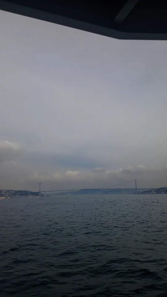 Gri bir günde Boğaz. Uzakta köprü, önümüzde bitmeyen dalgalar.