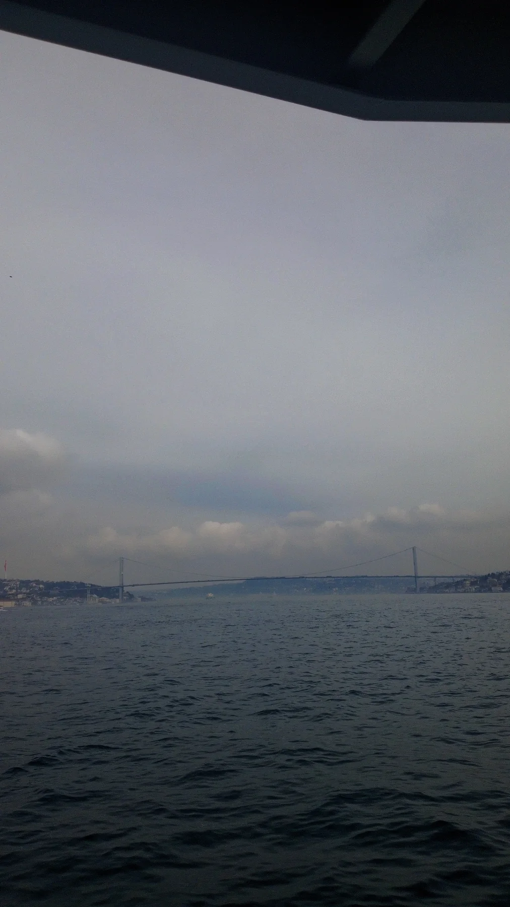 Gri bir günde Boğaz. Uzakta köprü, önümüzde bitmeyen dalgalar.