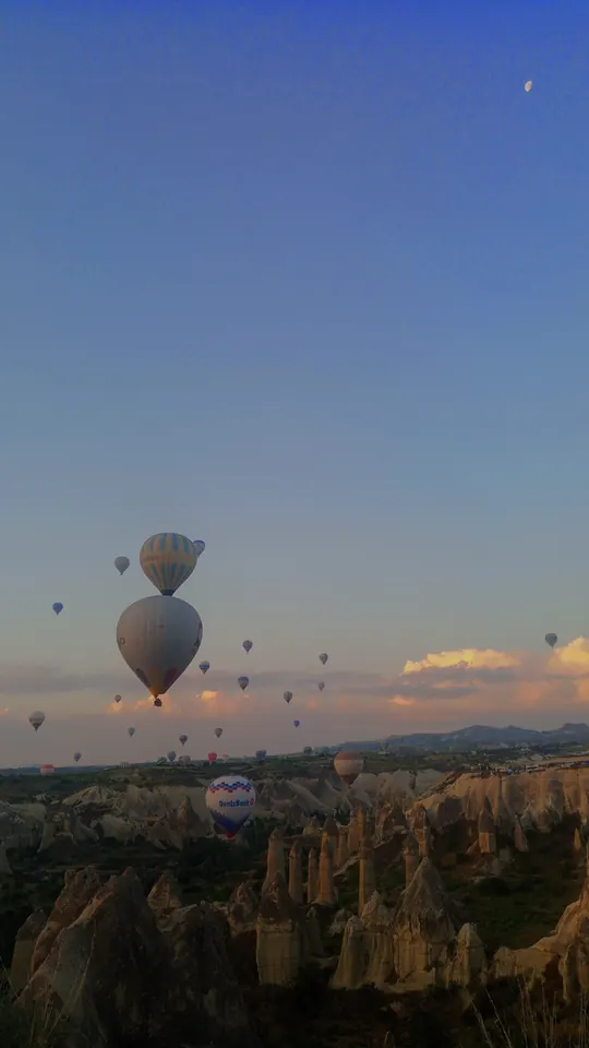 Kapadokya'da gün doğumu; peribacalarının üzerinde balonlar.