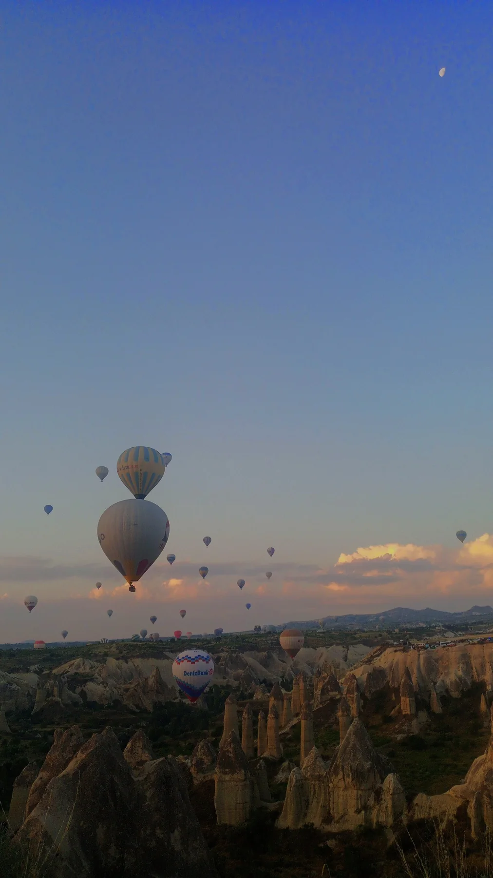 Kapadokya'da gün doğumu; peribacalarının üzerinde balonlar.