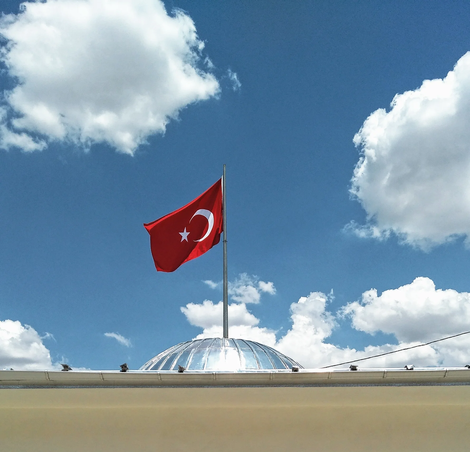 Rüzgârda bir bayrak, beyaz bulutlar.