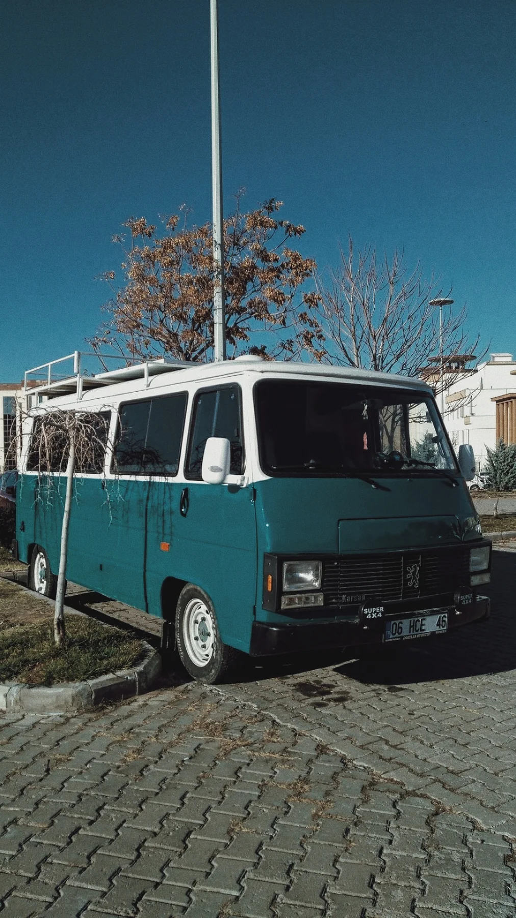 Sonbahar ağaçlarının altında eski, yeşil bir minibüs.